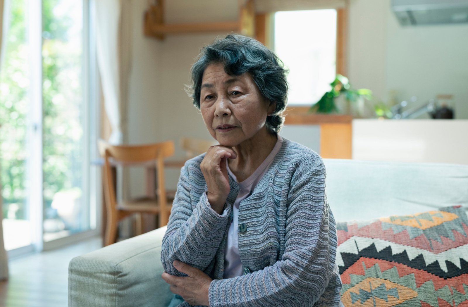 An older adult with dementia sits alone in their home before moving to a memory care community.