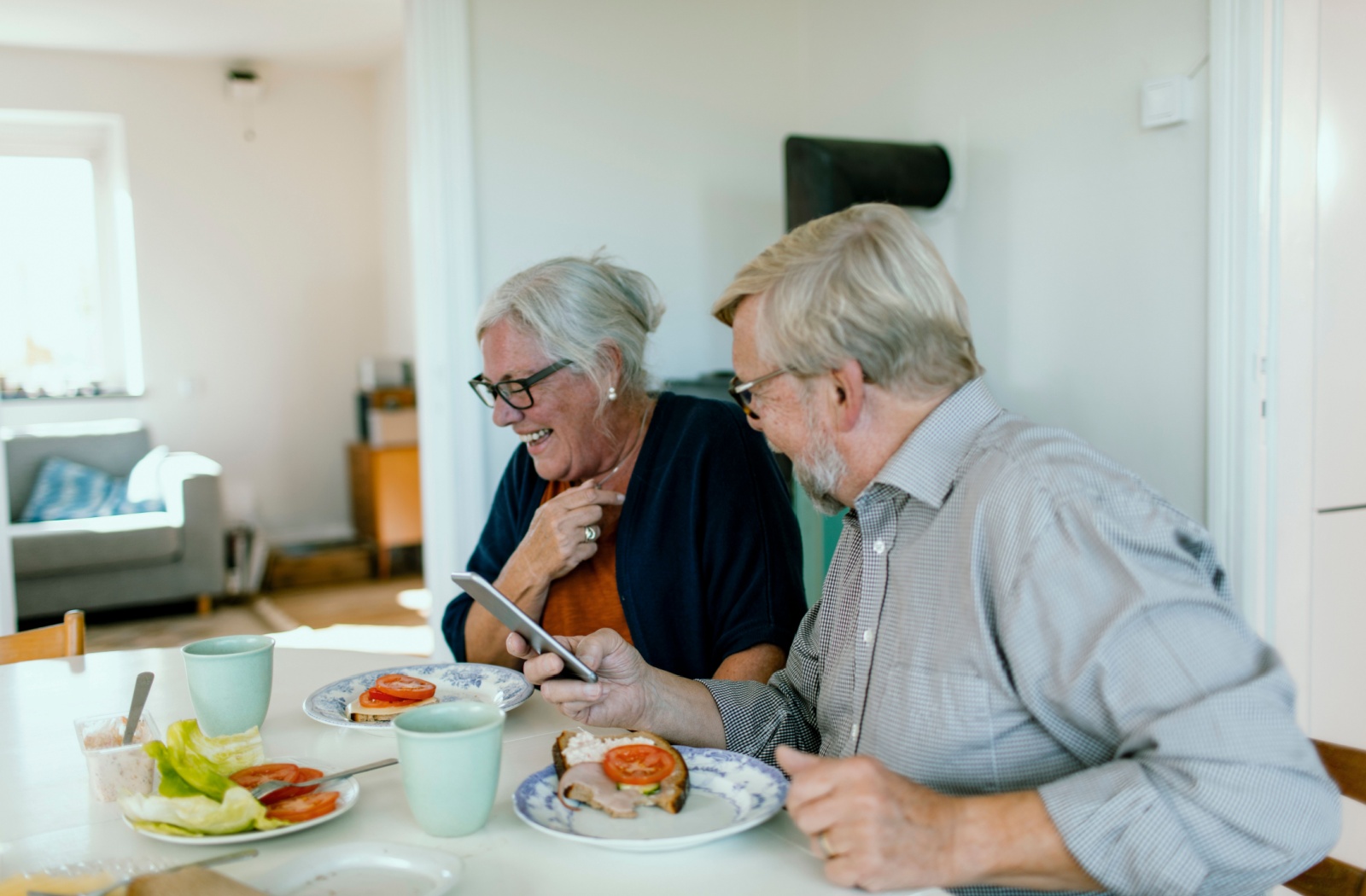 Two older adults in independent living laugh while enjoying a healthy breakfast with one another