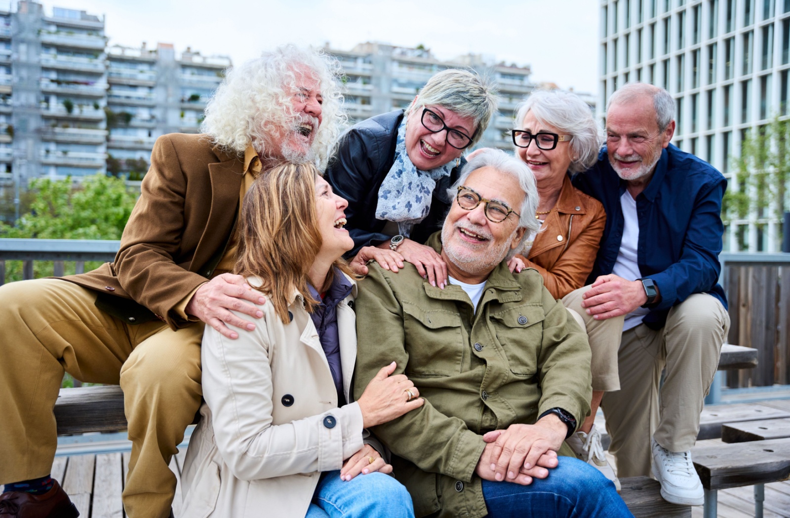 A group of 6 seniors sitting on a bench and laughing together, taking a break while on a day trip in Alabama.