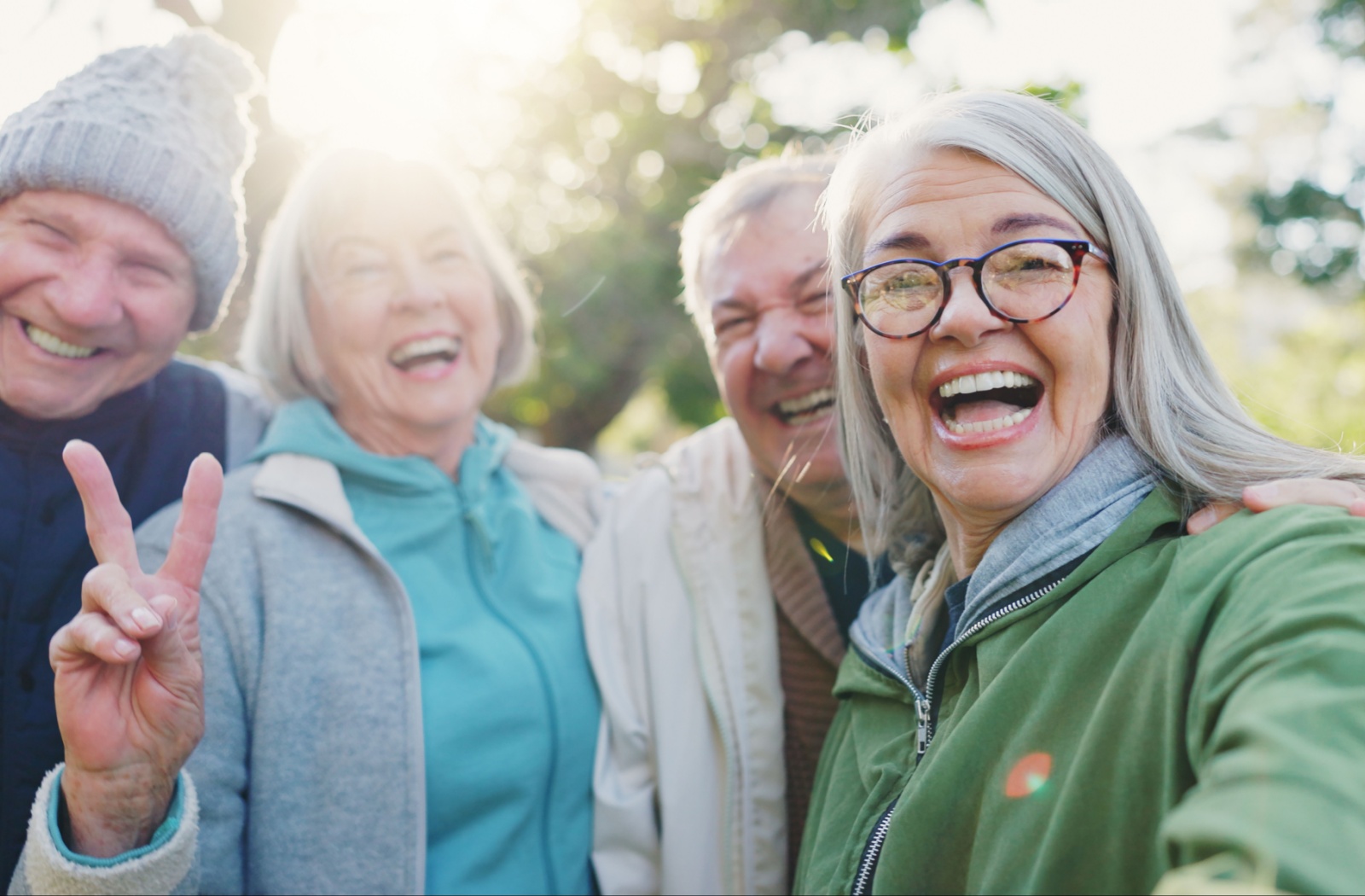 4 seniors outside in a park taking a selfie photo together, smiling and laughing on a day trip in Alabama.