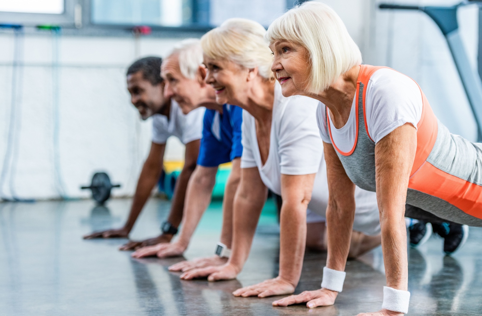 A group of older adults in a row performing a plank exercise during a fitness class to strengthen their core.