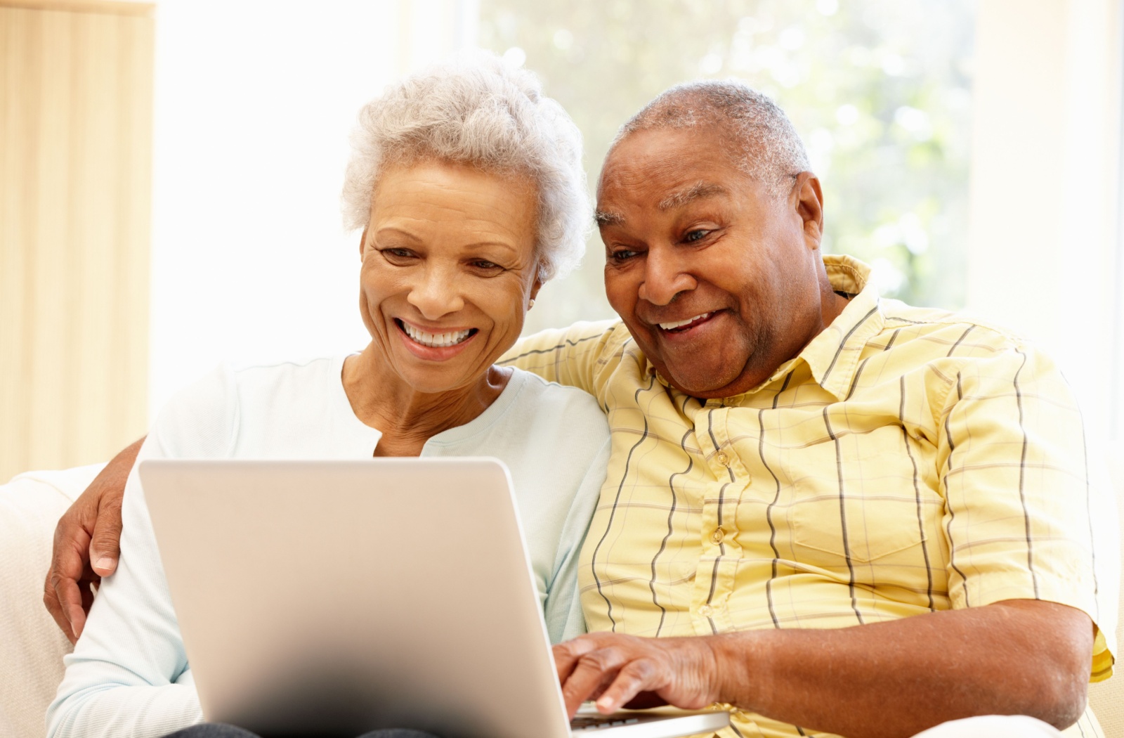 A happy senior couple enjoys talking to their loved ones safely online with their laptop.