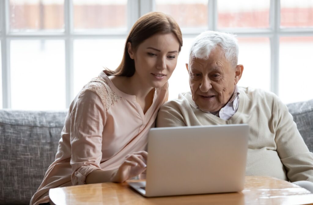 An adult child teachs their senior parent about online safety on their laptop.