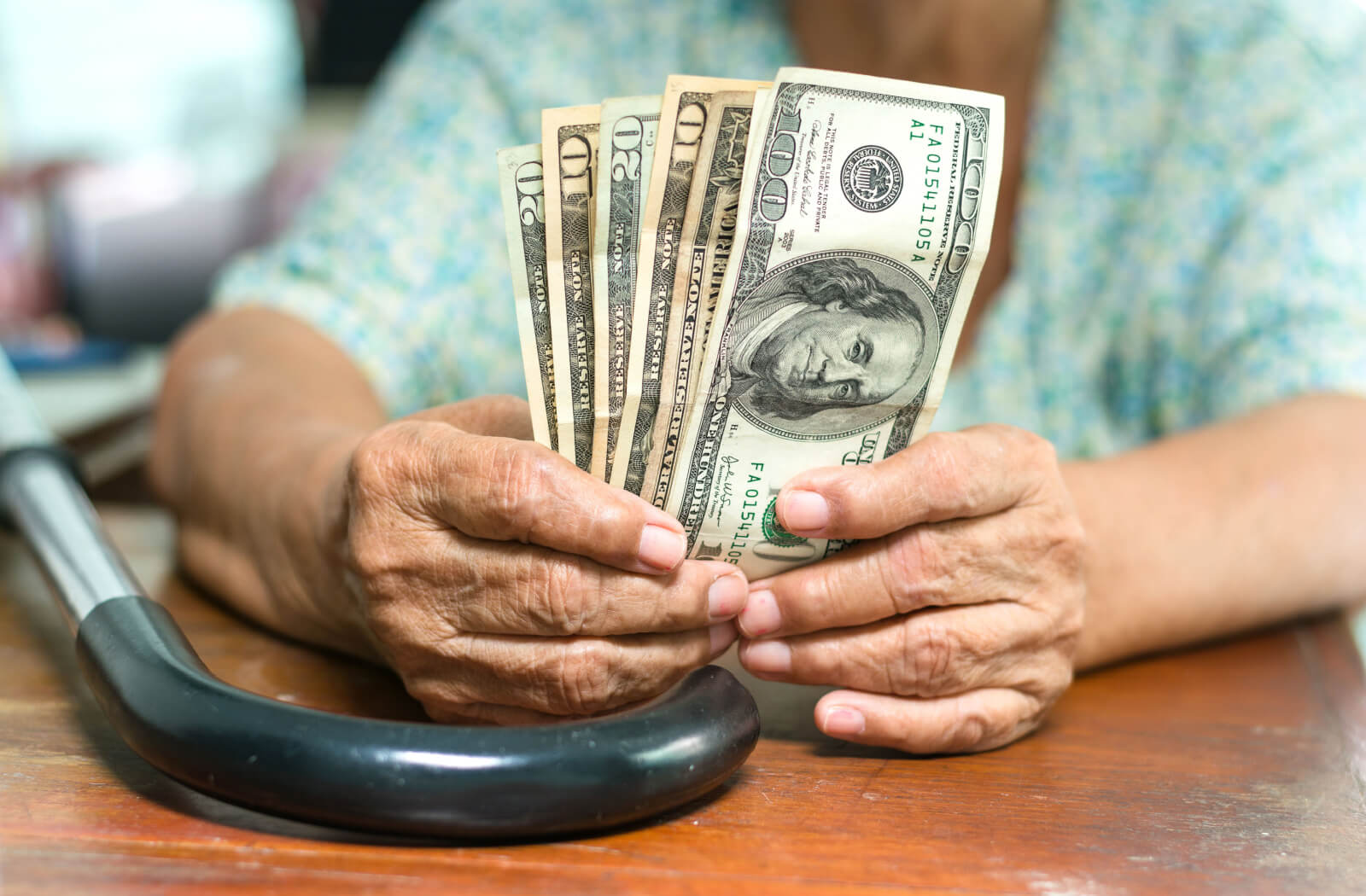 A close-up image of an older adult holding different bills.