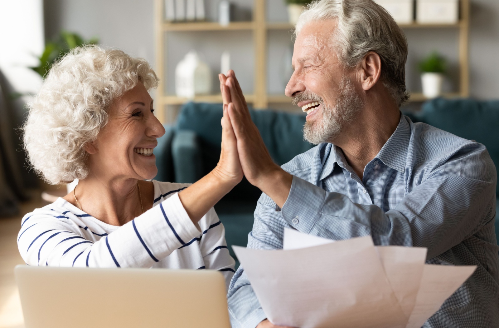 An older couple high-fiving after reviewing their monthly budget together.